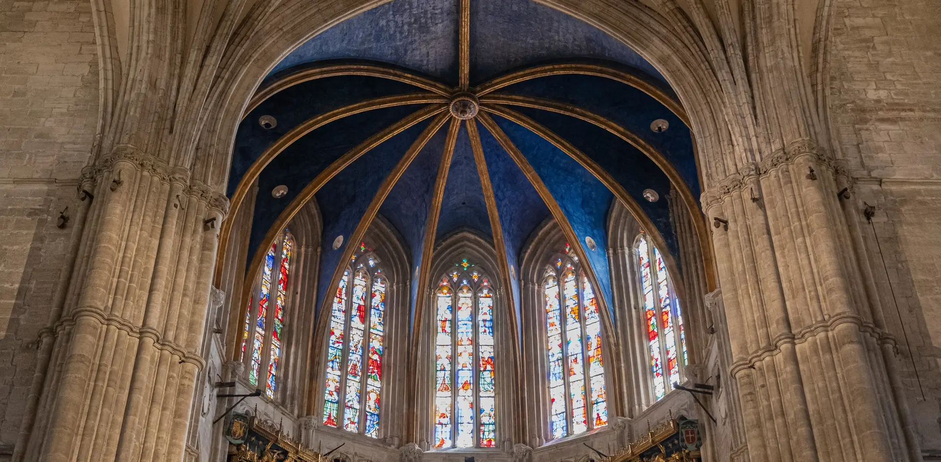 Interior de la Catedral de Oviedo, con su impresionante bóveda azul estrellada y vidrieras góticas llenas de color.