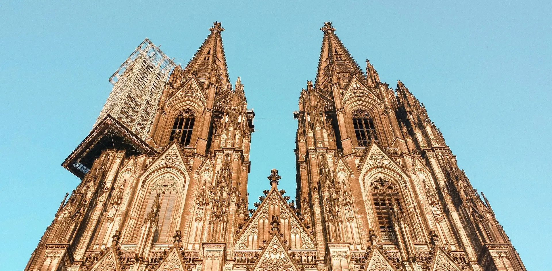 Torres gemelas de la Catedral de Colonia, Alemania, con detalles góticos y andamiaje en una de las fachadas.