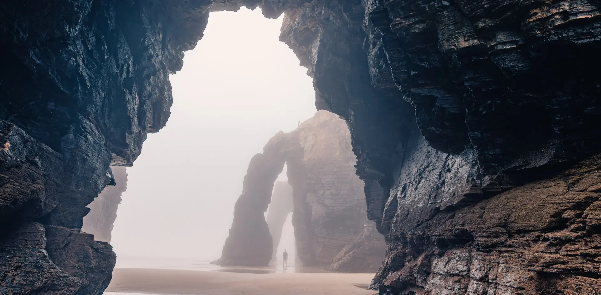 Arcos de piedra y acantilados de la Playa de las Catedrales, Ribadeo, Galicia, con ambiente brumoso.