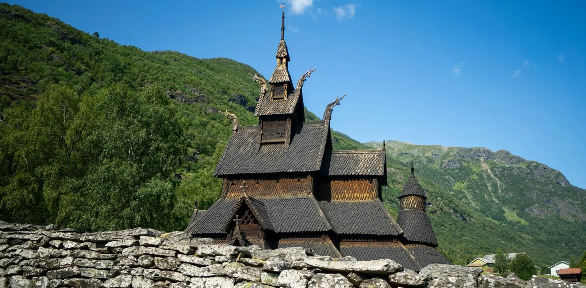 Iglesia de madera de Borgund en Noruega, arquitectura vikinga tradicional rodeada de montañas y naturaleza verde. 