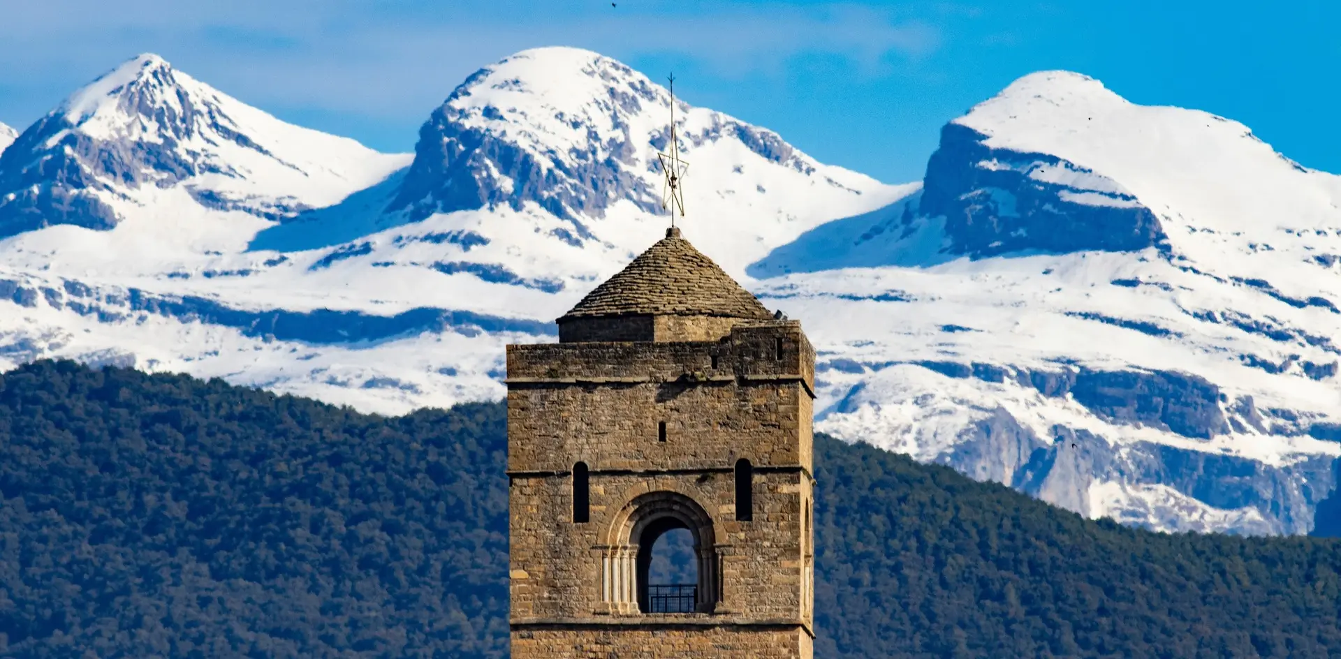 Primer plano de la torre de Aínsa con los Pirineos nevados de fondo en Huesca.