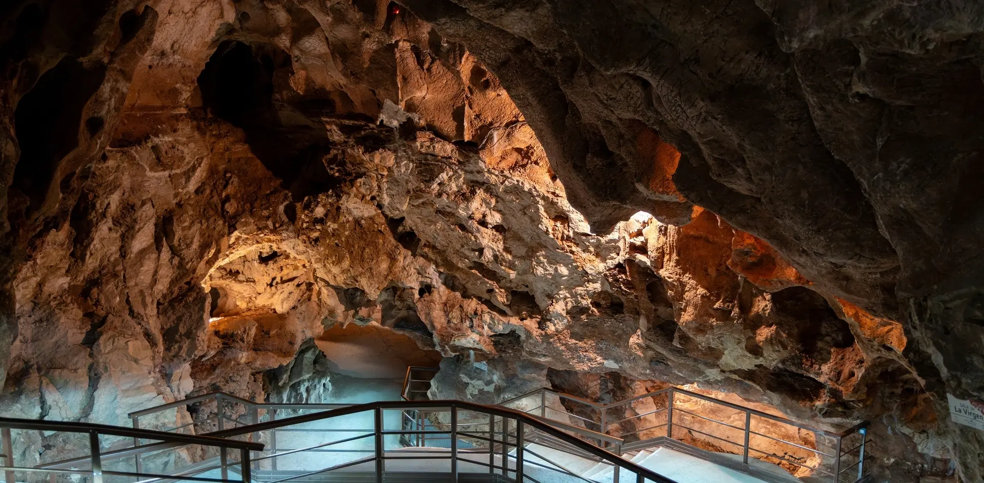 Pasarela y formaciones rocosas iluminadas en la Cueva del Tesoro, Málaga.