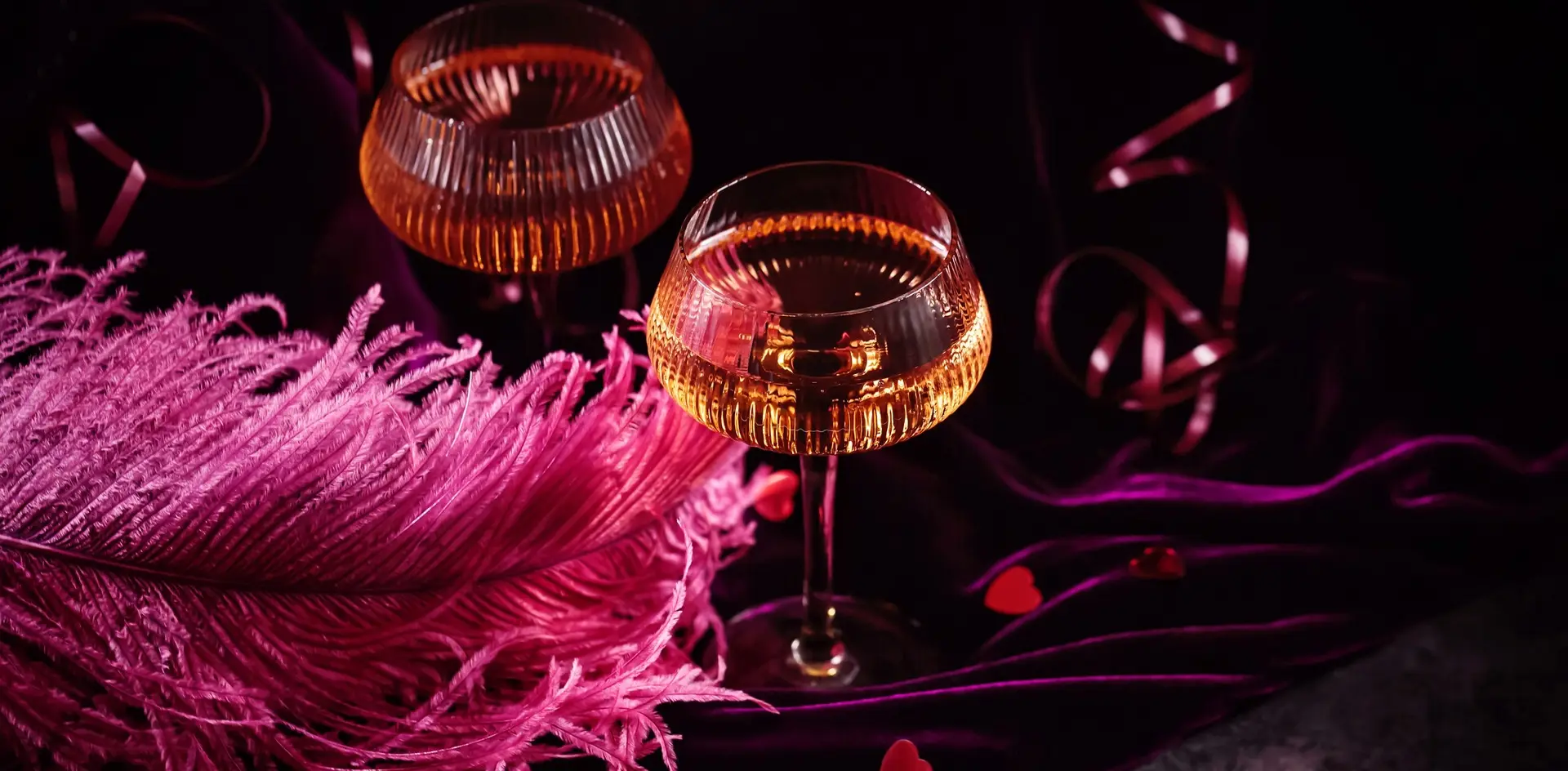 Dos copas de champán sobre terciopelo púrpura con plumas rosas en París