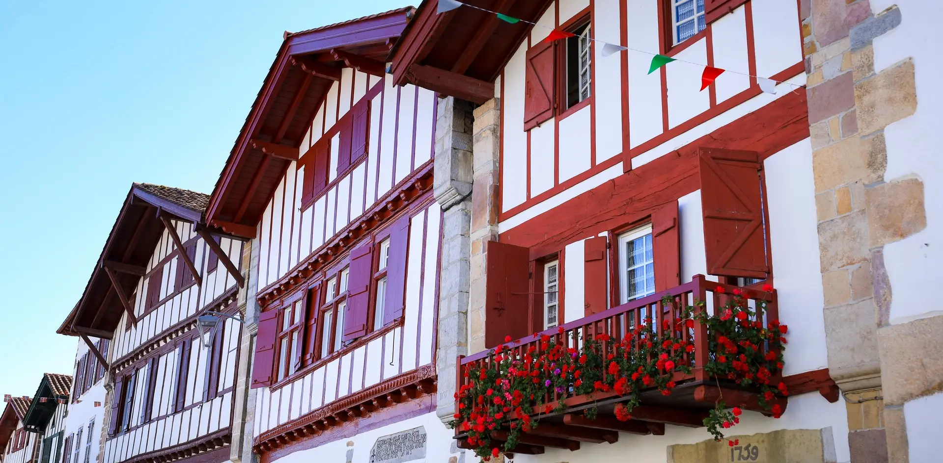 Casas tradicionales con entramado rojo y flores en balcones en Ainhoa, pueblo del País Vasco francés.