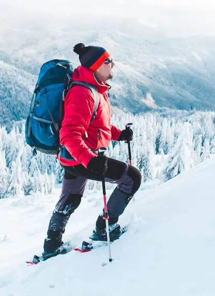 Hombre con chaqueta roja y mochila haciendo una ruta en raquetas de nieve por Sierra Nevada - Ruta en Raquetas de Nieve por Sierra Nevada - Actividades,  Experiencia al aire libre, Ocio y Turismo activo Buendía Andalucía 