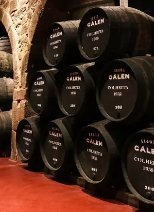 Barricas de vino de Oporto Cálem alineadas en una bodega tradicional de piedra.