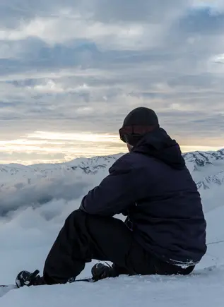 Chico sentando contemplado las vistas de las montañas.