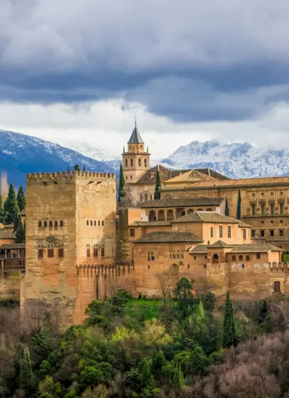 La Alhambra domina la ciudad de Granada, con sus imponentes murallas y torres, rodeada de jardines que reflejan su esplendor.