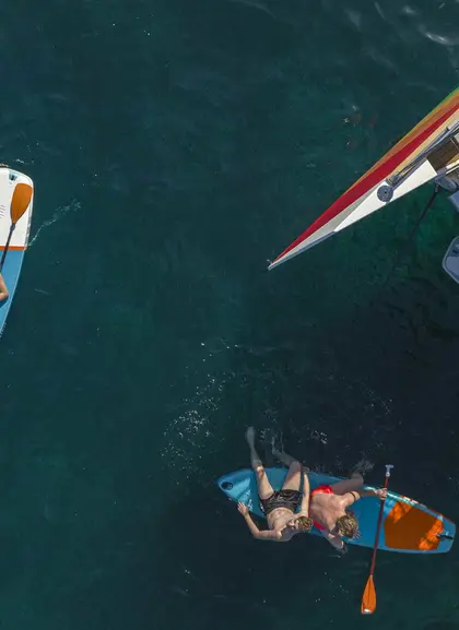Gente disfrutando del sol mientras se relajan sobre tablas de kayak, flotando en las aguas de la isla de Mallorca.