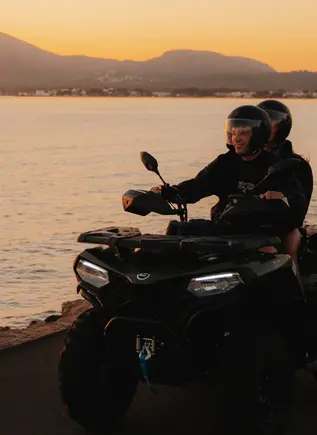 Dos personas montan en quad por la costa mallorquina al atardecer
