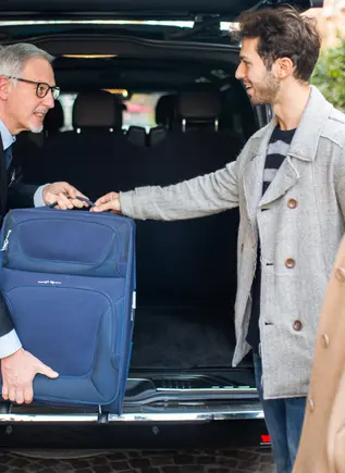 El conductor ayuda con la maleta a una pareja en el Aeropuerto Internacional Rafel Núñez.