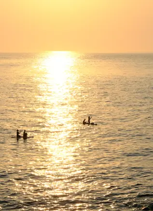 Precioso atardecer en Mallorca con personas haciendo paddle surf