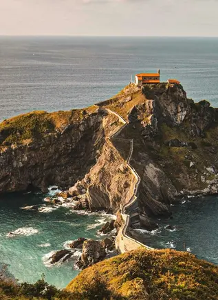 Vista aérea de San Juan de Gaztelugatxe en la costa vasca, con su camino de piedra serpenteante sobre el mar Cantábrico.