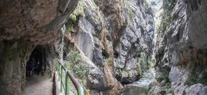 Senderistas caminando por la Ruta del Cares junto al río en los Picos de Europa, Asturias