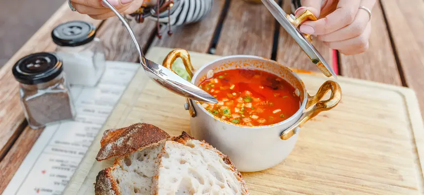 Goulash húngaro servido en olla tradicional con pan en una mesa de Budapest