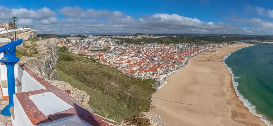 Panorámica de Nazaré con su amplia playa y casas junto al acantilado.