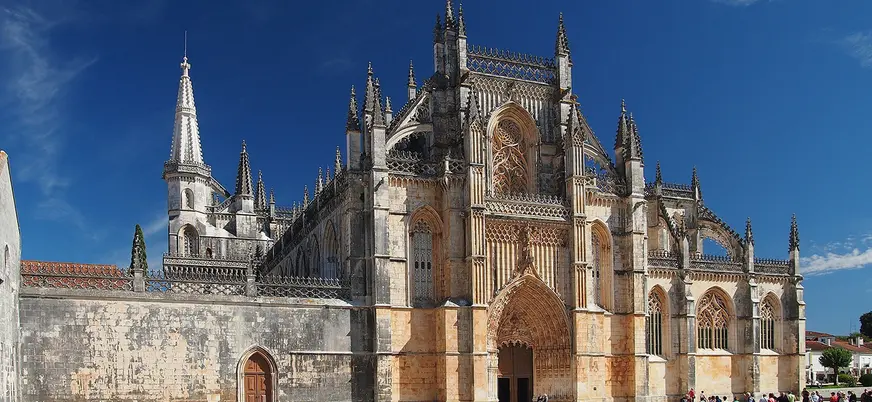 Fachada gótica del Monasterio de Batalha bajo un cielo azul despejado.