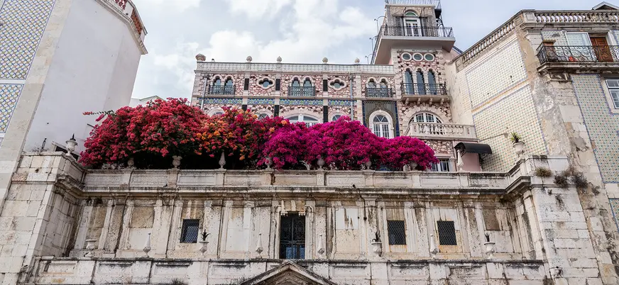 Fachada con flores y azulejos del Chafariz d'El Rei en el barrio de Alfama, Lisboa