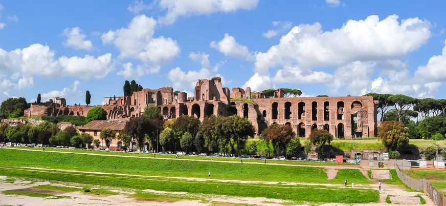 Ruinas romanas en la colina Palatina con estructuras de ladrillo y paisaje verde al fondo.
