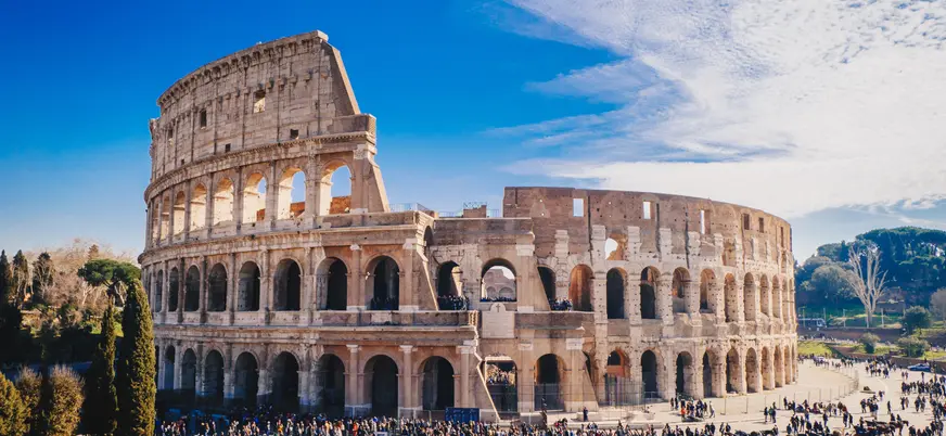 Vista del Coliseo romano con turistas alrededor bajo cielo despejado.