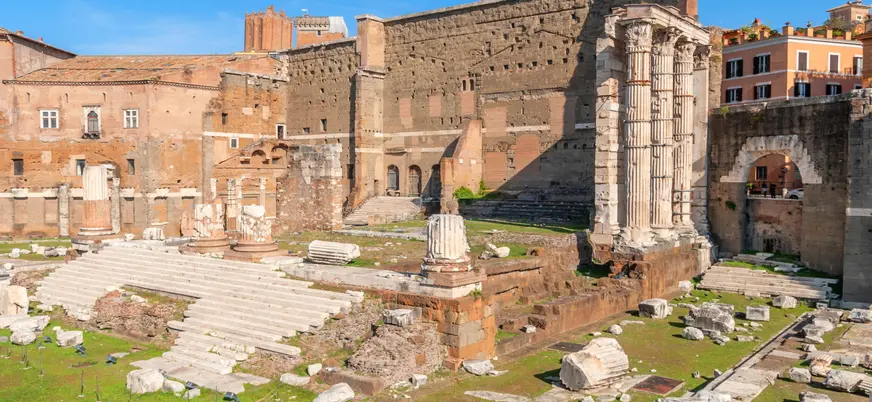 Ruinas del Foro de Augusto con columnas corintias y muros antiguos rodeados de arquitectura romana.
