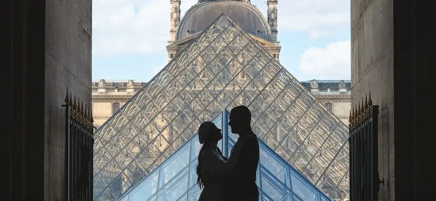 Pareja en silueta frente a la Pirámide del Louvre en París.