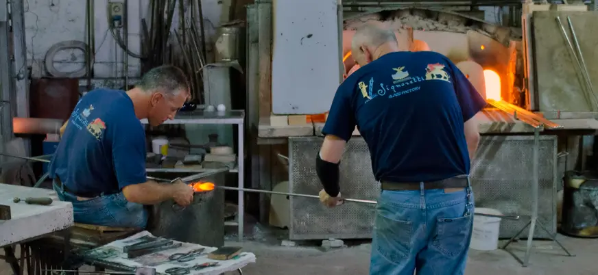 Artesanos trabajando vidrio soplado en un taller tradicional de Murano, Venecia