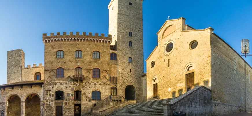 Plaza medieval en San Gimignano con torre de piedra y iglesia, Toscana, Italia.