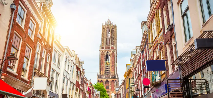 Calle típica de Utrecht, Países Bajos, con fachadas de edificios históricos a ambos lados y tiendas con toldos de colores. 