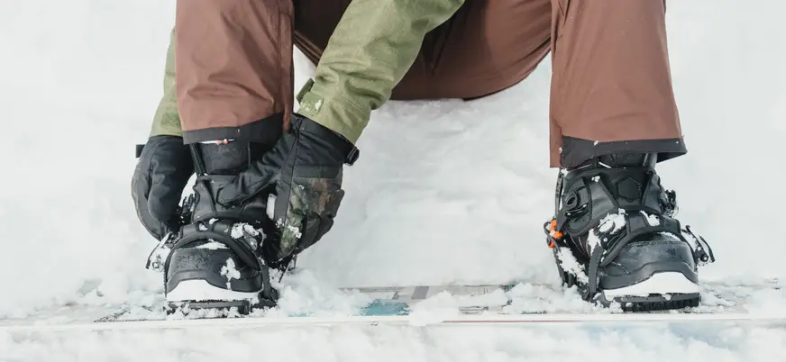 Botas de snowboard de alquiler ajustándose en Fuentes de Invierno, Asturias