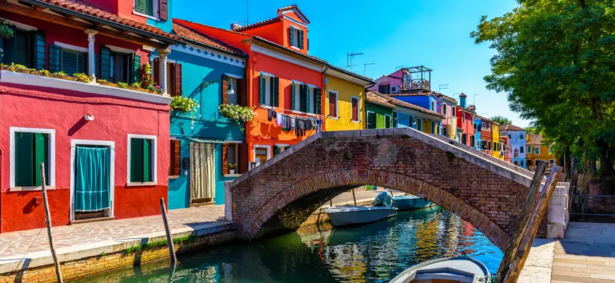 Puente de ladrillo y casas de colores junto al canal de Burano, Venecia