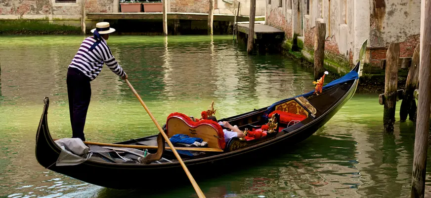 Góndola navegando por los canales de Venecia con gondolero guiando el paseo