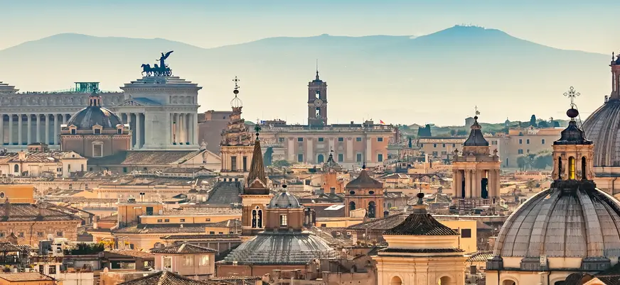 Panorámica de Roma con cúpulas históricas y el Altar de la Patria al fondo.