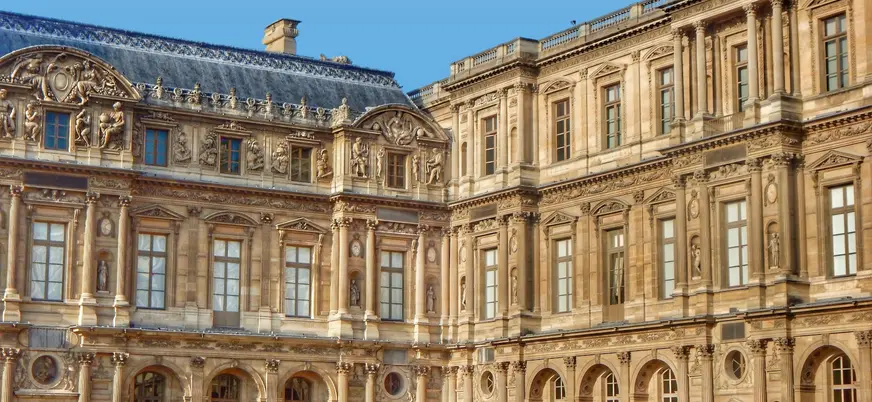 Palacio del Louvre, famoso museo de arte en París, con su icónica pirámide de vidrio en el patio central.