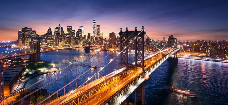 Puente de Brooklyn iluminado al anochecer con skyline de Manhattan, Nueva York, Estados Unidos