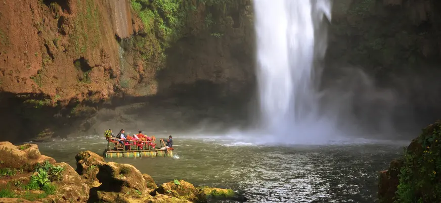 Balsa con visitantes frente a las Cascadas de Ouzoud de 110 metros en Marruecos