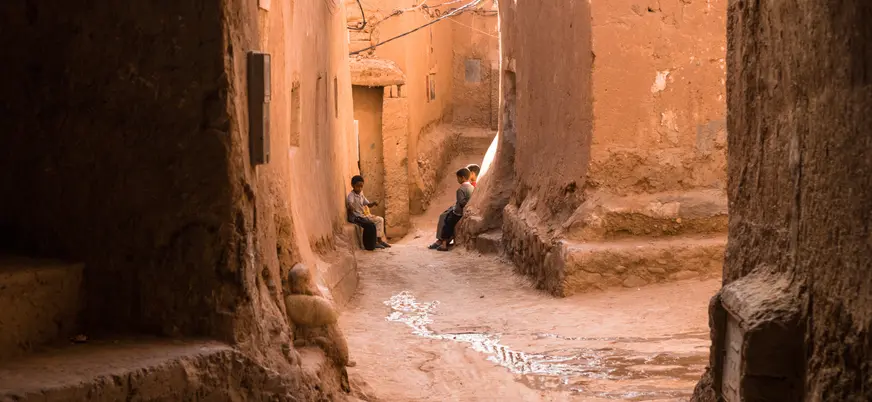 Calle tradicional de adobe en Ouarzazate con niños y arquitectura local