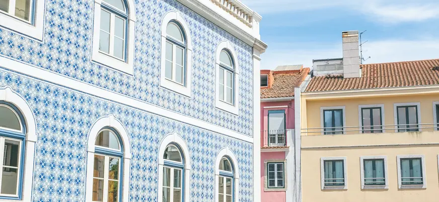 Fachadas lisboetas con azulejos azules y casas de colores al sol.