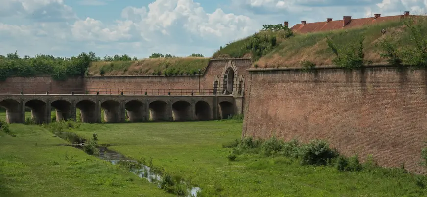Muros de ladrillo y un puente con arco sobre un foso en la Fortaleza de Terezín.
