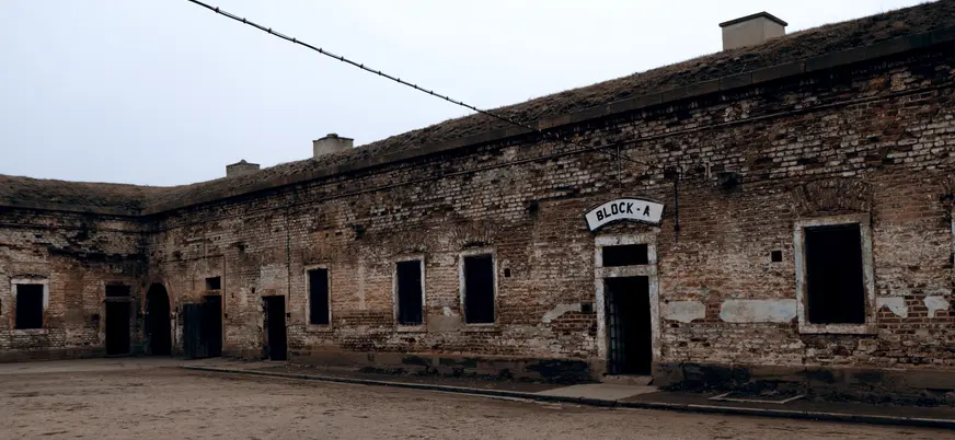 Patio de tierra con un edificio de ladrillo que dice BLOCK A en Terezín.