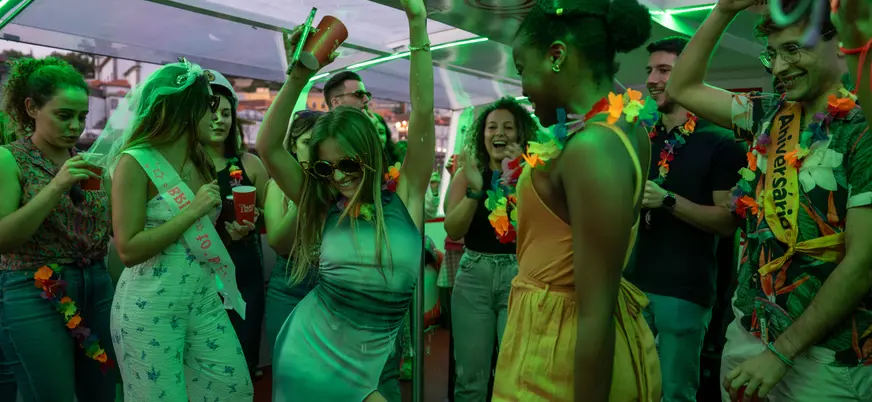 Grupo celebrando y bailando en una fiesta a bordo con luces verdes.