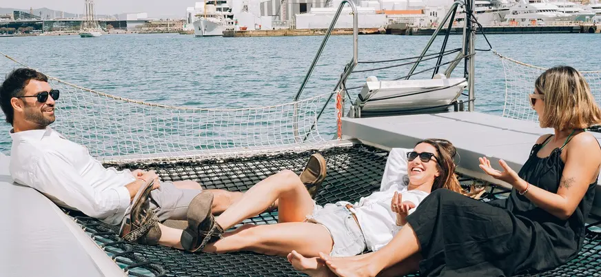 Pasajeros relajándose en la red del catamarán en el Port Vell de Barcelona.
