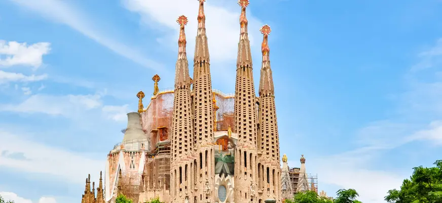 Vista frontal de la Sagrada Familia en Barcelona rodeada de vegetación