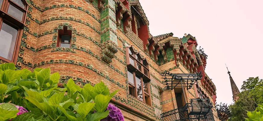 Fachada modernista de El Capricho de Gaudí en Comillas, Cantabria, con detalles cerámicos y flores.