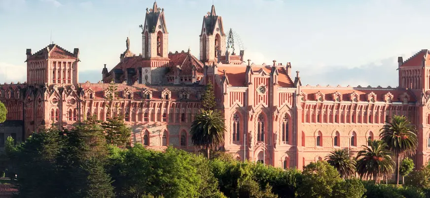 Vista del Seminario Mayor de Comillas en Cantabria, edificio neogótico rodeado de vegetación.