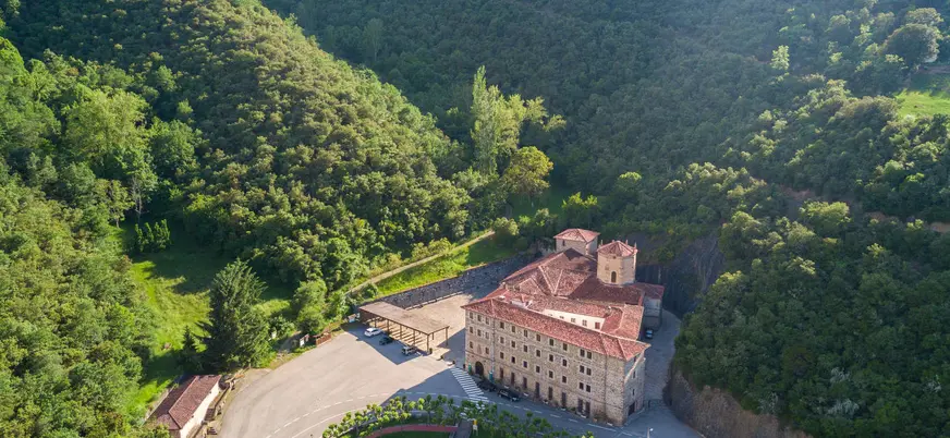 Vista aérea del Monasterio de Santo Toribio de Liébana rodeado de montes verdes.