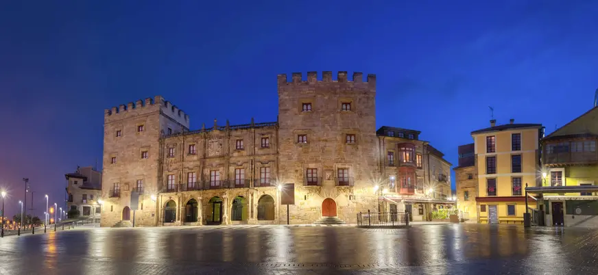 Palacio de Revillagigedo al anochecer, iluminado frente a la plaza en el casco histórico de Gijón, Asturias