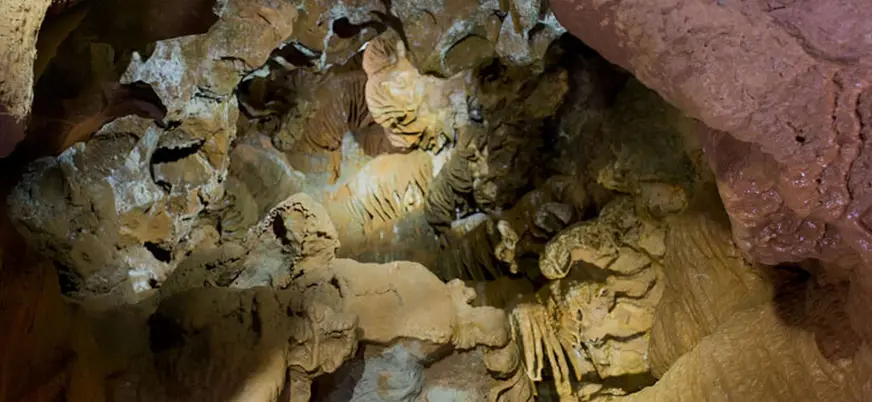 Interior de una cueva con formaciones geológicas como estalactitas, estalagmitas y coladas.