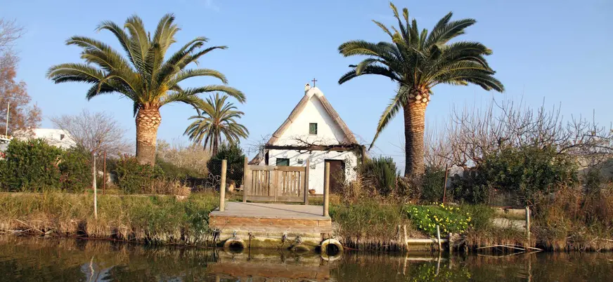 Barraca tradicional reflejada en el agua en la Albufera de Valencia