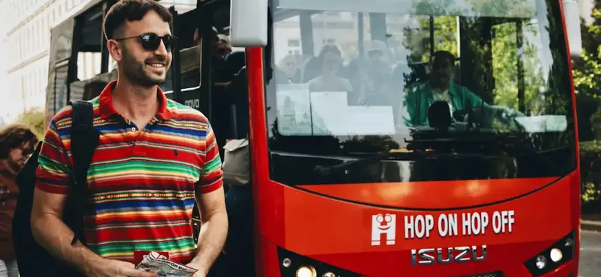 Un turista sonriendo sube a un autobús Hop-on Hop-off en Praga.